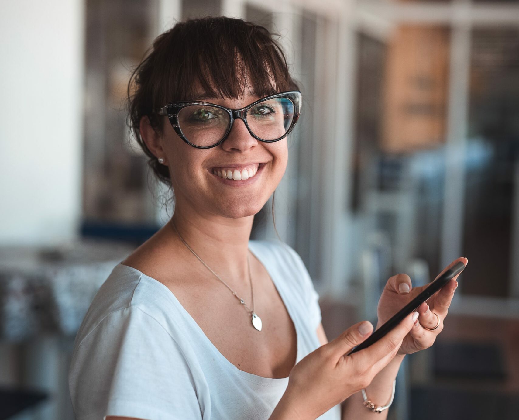 A smiling woman holding a smartphone.