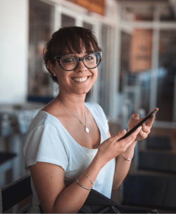 A smiling woman holding a smartphone.
