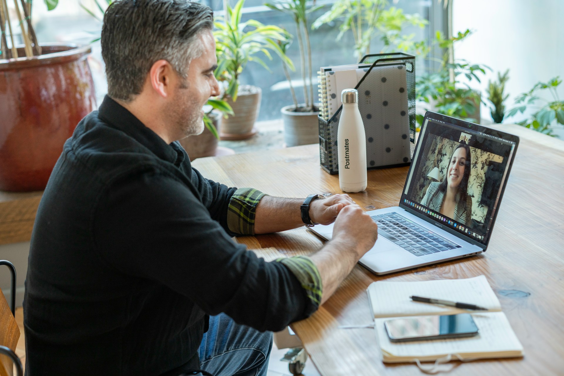 A smiling man talking to a lady on a video call on his laptop.