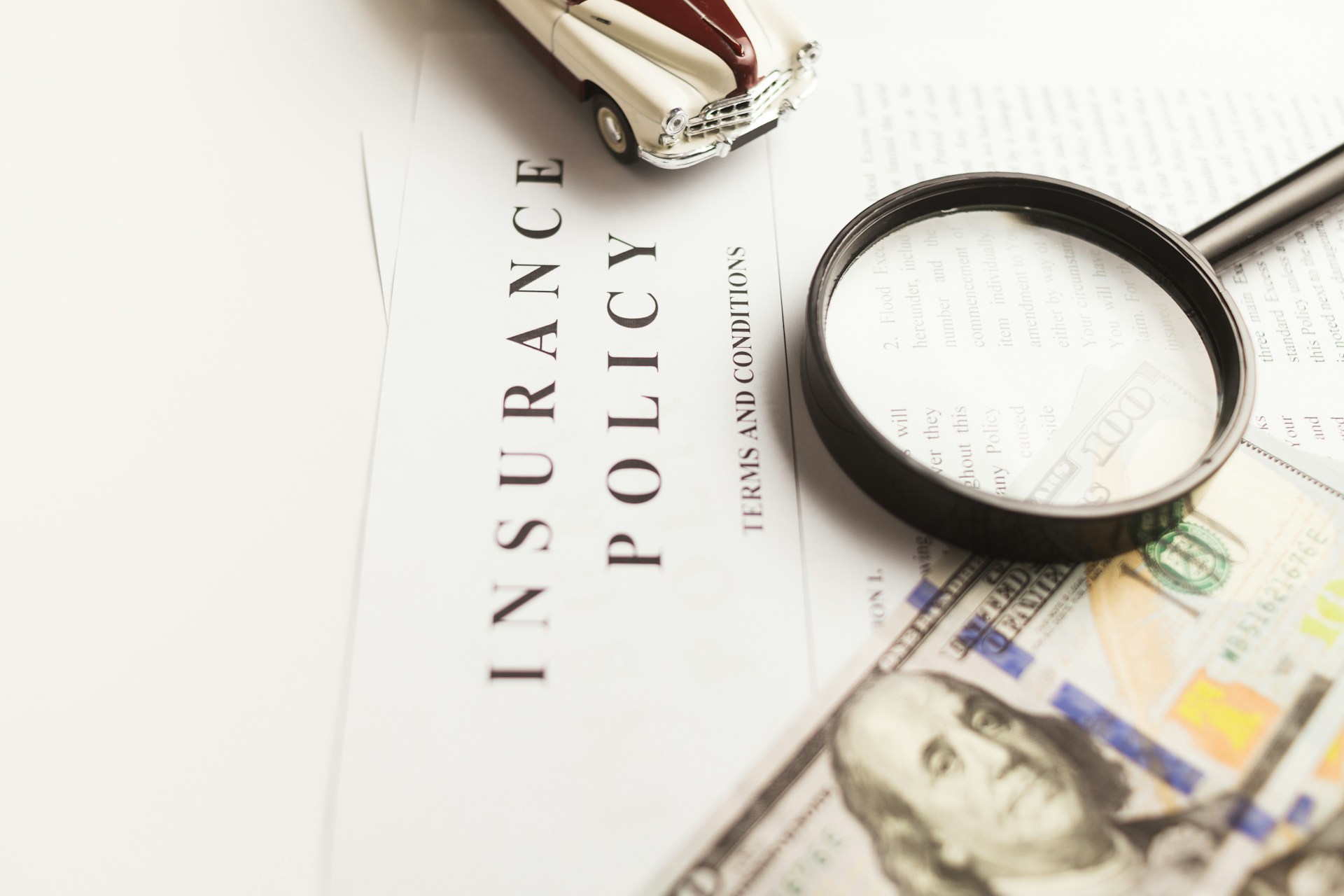 A magnifying glass and cash on a freelancer insurance policy document.